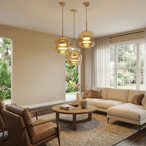 Kit 3 luminárias pendentes vidro âmbar dourado em sala de estar com sofá bege e vista para jardim tropical — SmartLuz