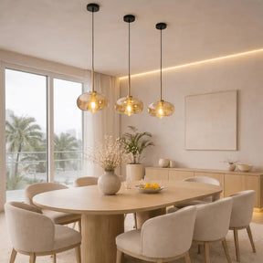 Três pendentes globo âmbar estilo industrial sobre mesa de jantar de madeira em ambiente minimalista com luz natural