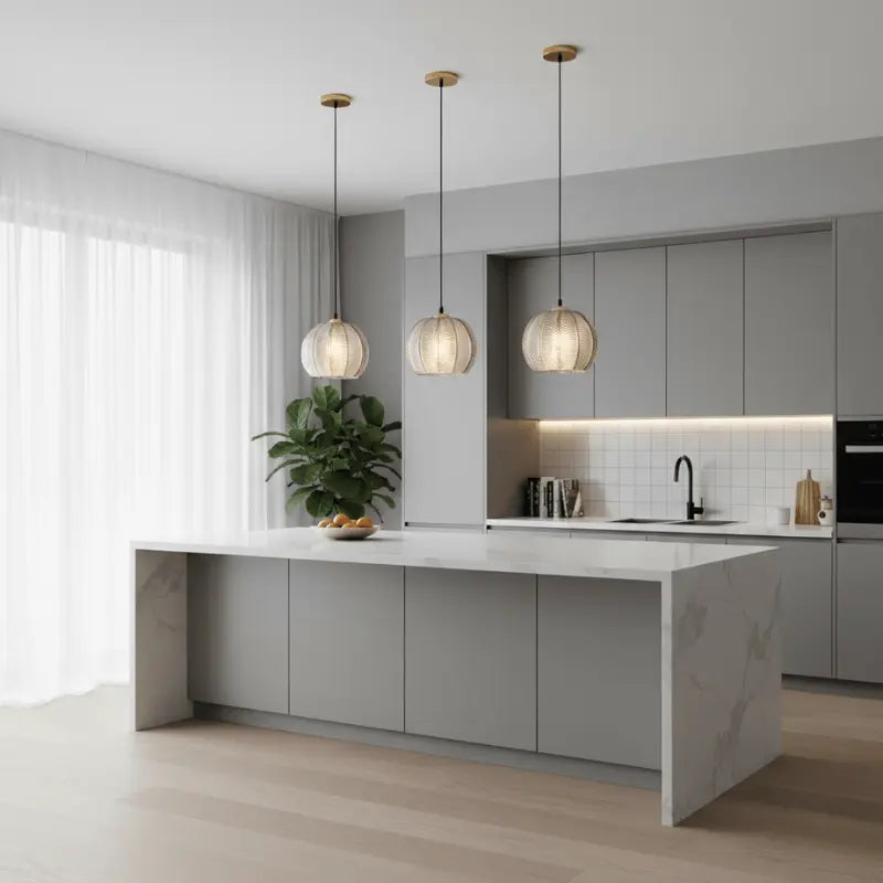 Três luminárias pendentes de vidro canelado âmbar decorando cozinha americana moderna com ilha de mármore e armários cinza
