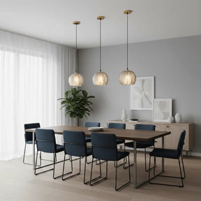 Três luminárias pendentes de vidro canelado âmbar sobre mesa de jantar com cadeiras azuis e buffet lateral