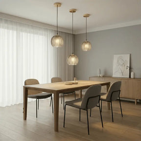 Três luminárias pendentes de vidro canelado âmbar sobre mesa retangular em sala de jantar estilo escandinavo com buffet de madeira 