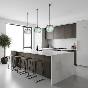 Três luminárias pendentes de vidro canelado verde decorando cozinha americana moderna com ilha e banquetas